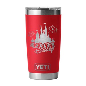 May include: A red insulated tumbler with a silver lid and base. The tumbler features a silver graphic of a castle, fireworks, and the word "Disney". The brand name "YETI" is displayed at the bottom.