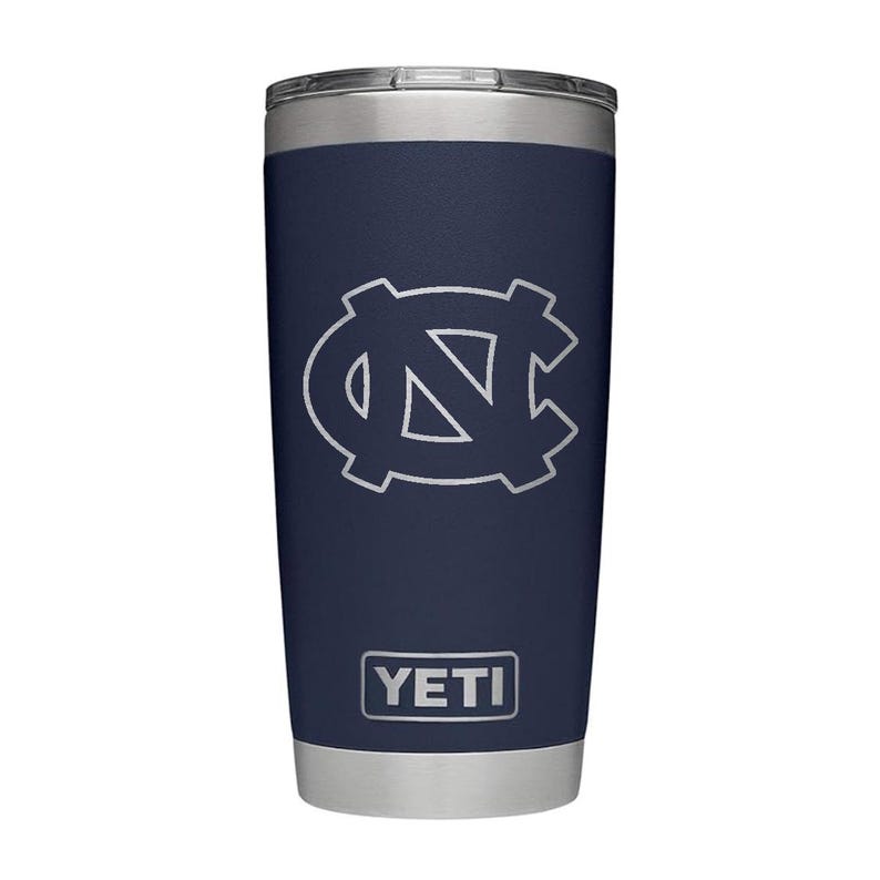 May include: Navy blue insulated tumbler with a silver lid and base. The tumbler features a white outline of the UNC logo and the brand name "YETI" in a white rectangular box.