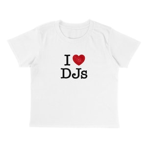 May include: White t-shirt with the text "I ♥ DJs" in black letters and a red heart symbol. The shirt has short sleeves and a crew neck.