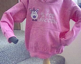 May include: Pink hooded sweatshirt with a white unicorn graphic and the text "U is for unicorn".