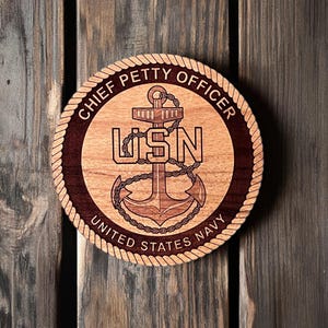 May include: A round wooden plaque with a rope border, featuring a carved anchor and the text "Chief Petty Officer US Navy United States Navy".