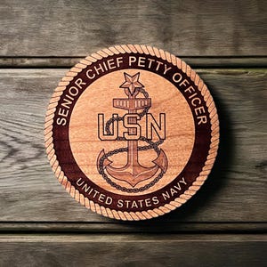 May include: A wooden plaque with a dark brown border and a rope design. The plaque features a stylized anchor with the text "USN" and the words "Senior Chief Petty Officer, United States Navy".