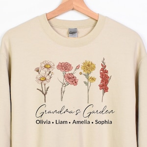 May include: A beige sweatshirt with a floral design and the text "Grandma's Garden" and "Olivia, Liam, Amelia, Sophia".