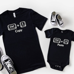 May include: Black t-shirts with white text and keyboard symbols. The larger shirt says "Ctrl + C Copy" and the smaller shirt says "Ctrl + V Paste".