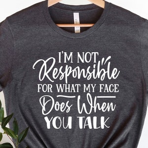May include: A dark grey t-shirt with white text that reads "I'm not responsible for what my face does when you talk."