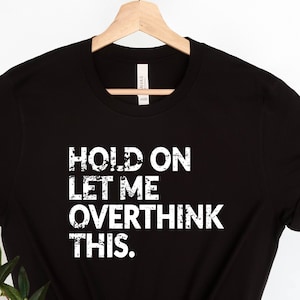 May include: Black t-shirt with white text that reads "HOLD ON LET ME OVERTHINK THIS."