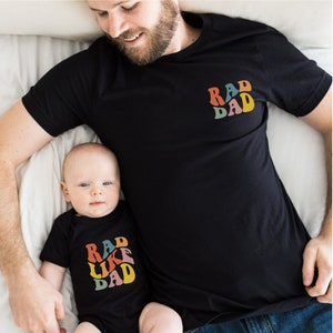 Peut inclure: Un père et son enfant portant des t-shirts noirs assortis avec un graphisme rétro qui dit "Rad Dad" et "Rad Like Dad".