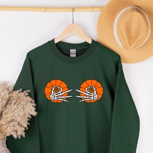May include: A dark green sweatshirt with a graphic of two orange pumpkins with skeleton hands reaching out from inside.