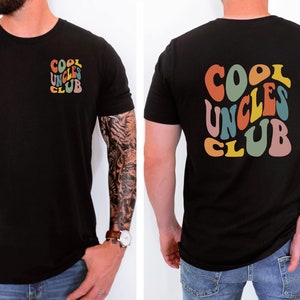 May include: Black t-shirt with a colourful "Cool Uncles Club" graphic on the back and a smaller version of the graphic on the front.