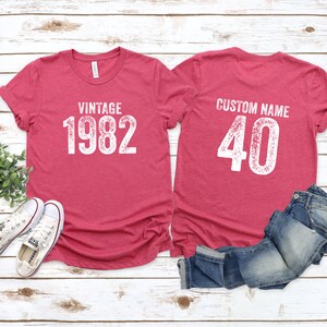 May include: Two red t-shirts with white text. The front shirt says "Vintage 1982". The back shirt says "Custom Name 40".
