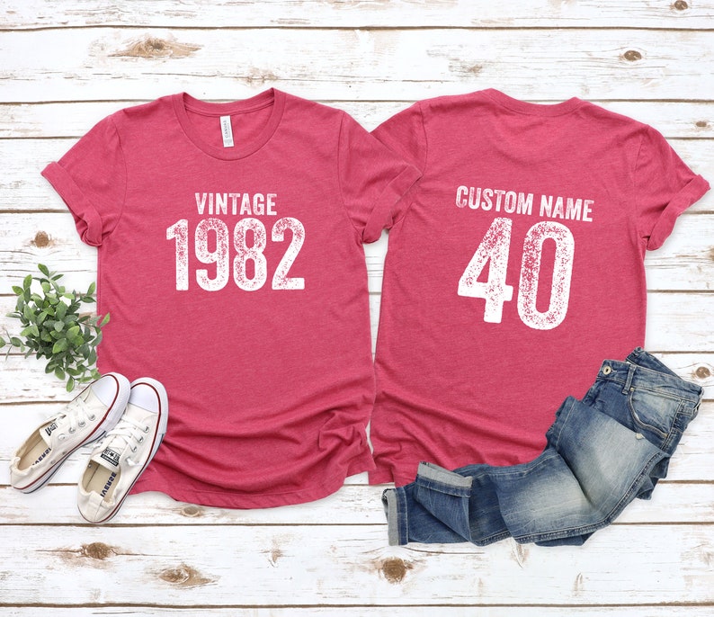 May include: Two red t-shirts with white text. The front shirt says "Vintage 1982". The back shirt says "Custom Name 40".