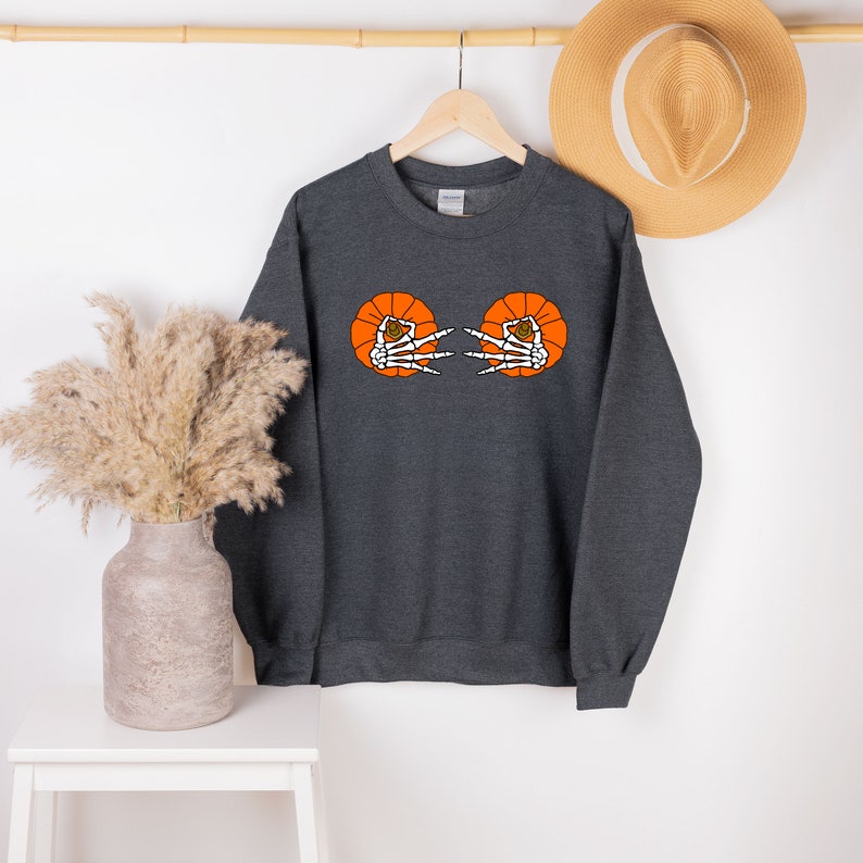 May include: A dark gray sweatshirt with a graphic of two orange pumpkins with skeleton hands reaching out from inside.