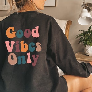 May include: Black sweatshirt with a colorful "Good Vibes Only" graphic on the back.