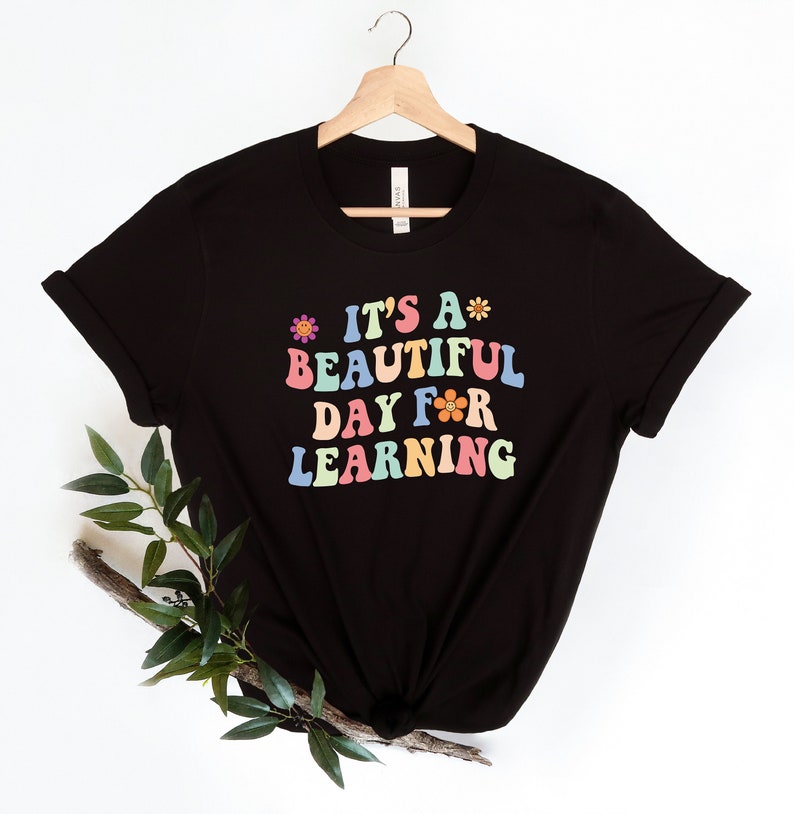 May include: Black t-shirt with a colorful graphic that says "It's a beautiful day for learning" with flower accents.