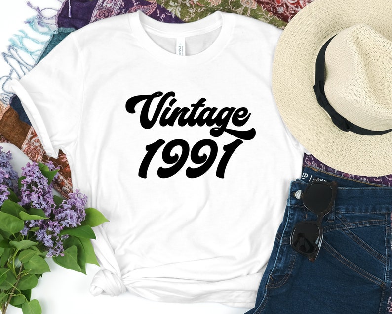 May include: White t-shirt with black text that reads "Vintage 1991" in a retro font.