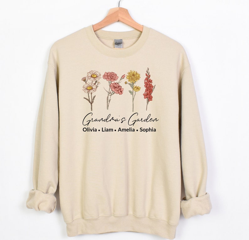 May include: A beige sweatshirt with a floral design and the text "Grandma's Garden" and "Olivia, Liam, Amelia, Sophia".