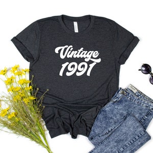 May include: A dark gray t-shirt with white text that reads "Vintage 1991".