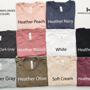 May include: A collection of Bella + Canvas unisex t-shirts in various colors, including heather peach, heather navy, heather dark gray, heather mauve, white, heather black, heather gray, heather olive, soft cream, and heather maroon. The shirts are laid out in rows of two, with the color names printed below each shirt.