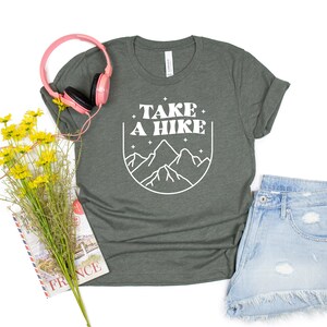 May include: A dark green t-shirt with a white graphic design that says "Take a Hike" with a mountain range illustration.