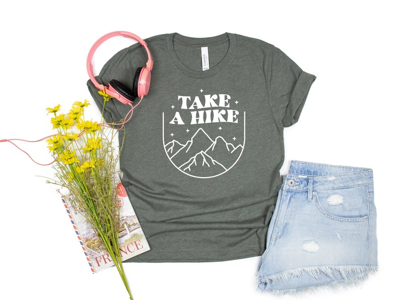 May include: A dark green t-shirt with a white graphic design that says "Take a Hike" with a mountain range illustration.