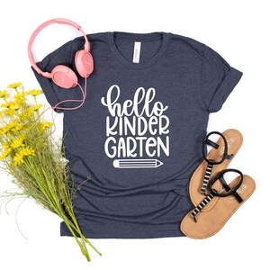 May include: A navy blue t-shirt with the text "hello kindergarten" in white lettering and a white pencil graphic.