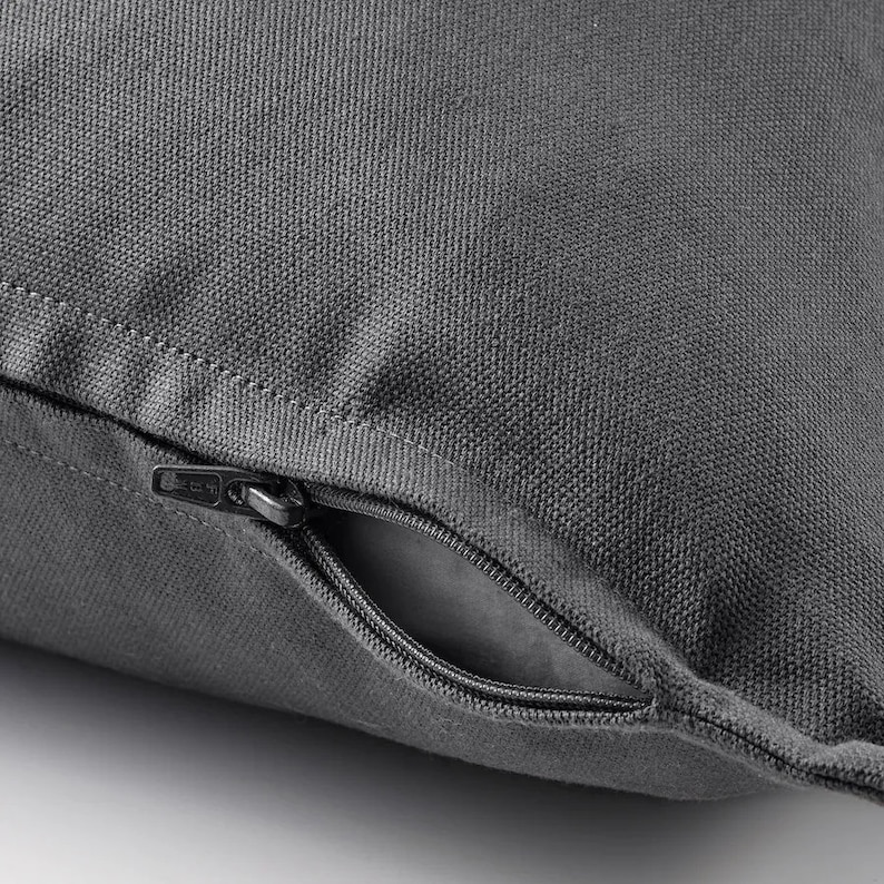 May include: A gray pillow with a zipper closure. The zipper is open and the inside of the pillow is visible.