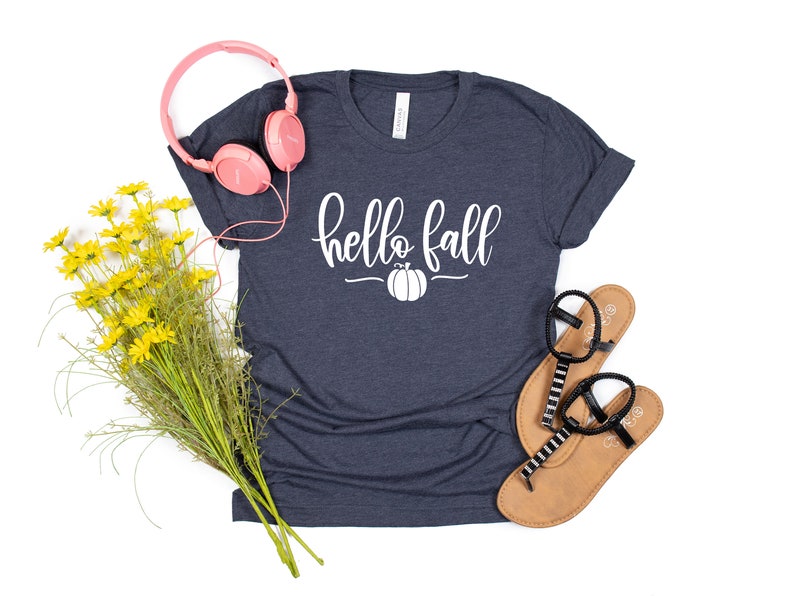 May include: A navy blue t-shirt with the text "hello fall" in white lettering and a white pumpkin graphic.