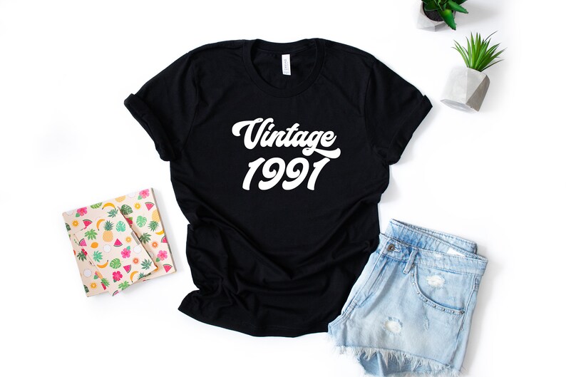 May include: Black t-shirt with white text that reads "Vintage 1991" in a retro font.