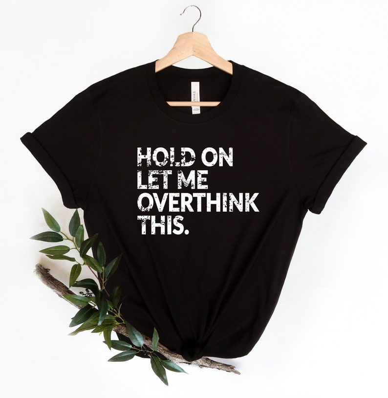 May include: Black t-shirt with white text that reads "HOLD ON LET ME OVERTHINK THIS."