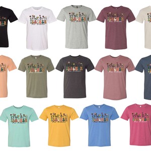 Pode incluir: Uma cole&ccedil;&atilde;o de 18 camisetas em v&aacute;rias cores, com o texto "TEACHER" com detalhes florais e o nome "Mrs. Anderson".