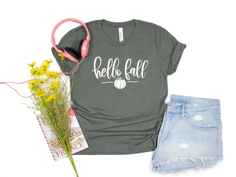 May include: A dark green t-shirt with the text "hello fall" in white lettering and a small white pumpkin graphic.