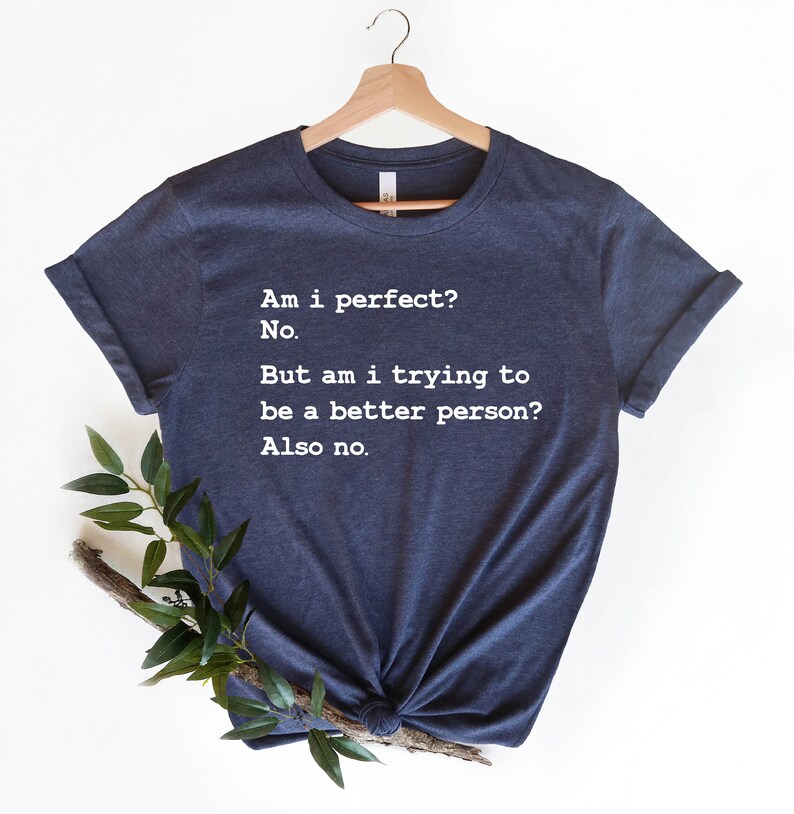 Puede incluir: Una camiseta azul marino con texto blanco que dice: "&iquest;Soy perfecto? No. Pero, &iquest;estoy tratando de ser una mejor persona? Tampoco."