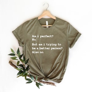 Puede incluir: Una camiseta verde con el texto "&iquest;Soy perfecto? No. Pero, &iquest;estoy tratando de ser una mejor persona? Tampoco."