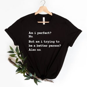 Puede incluir: Camiseta negra con texto blanco que dice: "&iquest;Soy perfecto? No. Pero, &iquest;estoy tratando de ser una mejor persona? Tampoco."