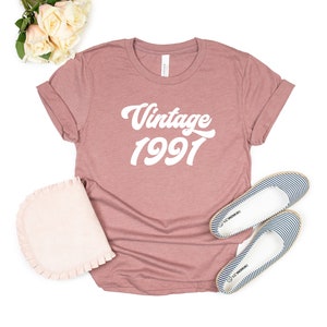 May include: A mauve colored t-shirt with the text "Vintage 1991" in white.