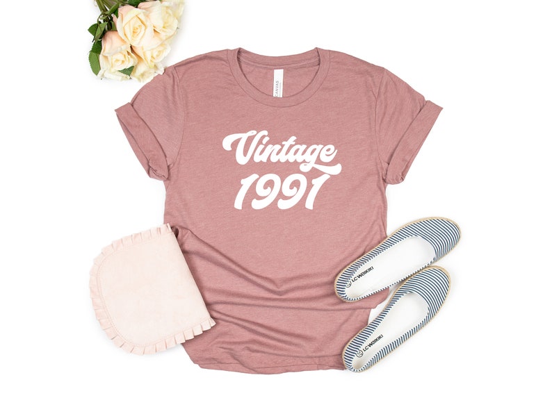 May include: A mauve colored t-shirt with the text "Vintage 1991" in white.