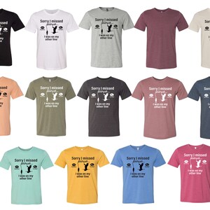 May include: A set of 12 t-shirts in various colors featuring a fishing-themed graphic with the text "Sorry I missed your call. I was on my other line."