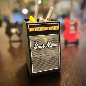May include: Black and silver guitar amplifier-shaped desk organizer with a speaker grille and the text "Your Name" on the front.
