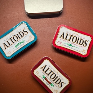 Puede incluir: Tres latas de mentas Altoids, una en rojo, una en azul y una en plata. Las latas est&aacute;n etiquetadas con el nombre de la marca y el sabor: Canela, Menta verde y Menta piperita.