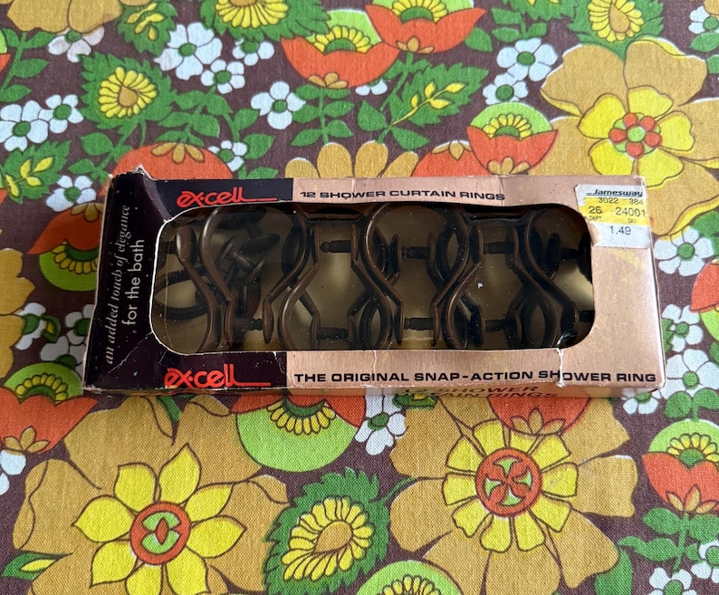 May include: A vintage box of Excell shower curtain rings. The box is brown and black with the text "an added touch of elegance for the bath" and "THE ORIGINAL SNAP-ACTION SHOWER RING". The box contains bronze-colored shower curtain rings.