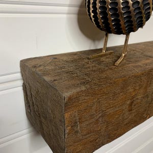 May include: A rustic wooden shelf with a dark brown stain. The shelf has a rough, textured surface and is ideal for displaying decorative items.