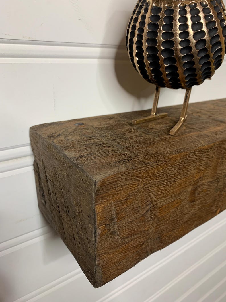 May include: A rustic wooden shelf with a dark brown stain. The shelf has a rough, textured surface and is ideal for displaying decorative items.