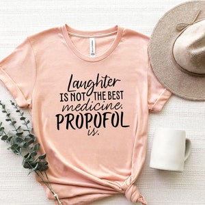May include: A pink t-shirt with the text "Laughter is not the best medicine. Propofol is." printed in black.