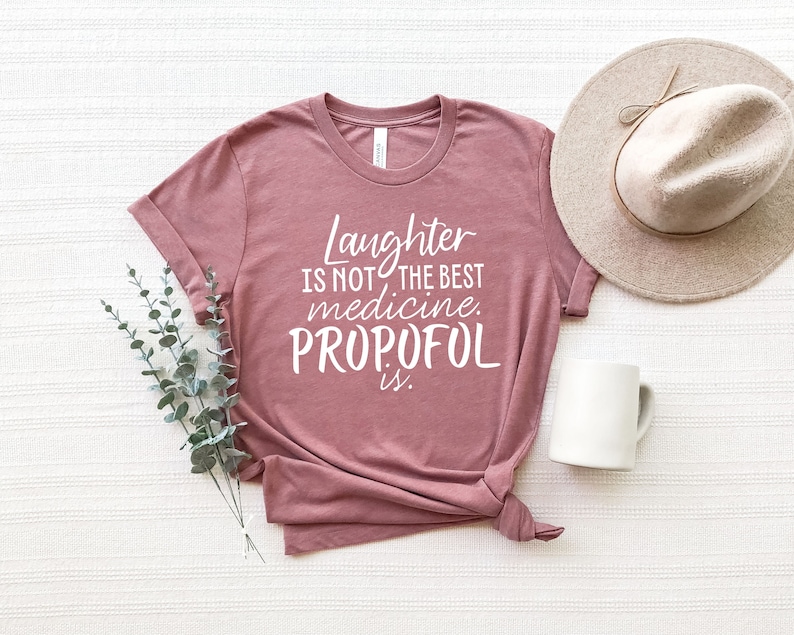 May include: A mauve t-shirt with the text "Laughter is not the best medicine. Propofol is." printed in white.