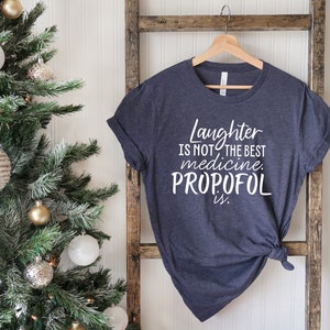 May include: A dark blue t-shirt with white text that reads "Laughter is not the best medicine. Propofol is."