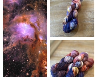 Puede incluir: Una madeja de hilo teñido a mano con una paleta de colores variados de azul marino profundo, violeta vibrante, naranja cálido y blanco crema, mostrada junto a una imagen de nebulosa cósmica que refleja el complejo esquema de color del hilo.