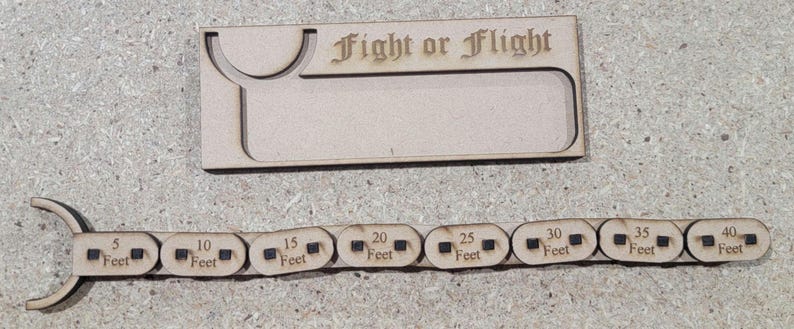 Puede incluir: Un accesorio de juego de madera Fight or Flight. El conjunto incluye una pieza rectangular con el texto "Fight or Flight" y una ranura curva, y una regla segmentada marcada de 1,5 a 12,2 metros.