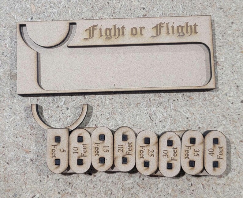 Puede incluir: Accesorio de juego de madera cortado con l&aacute;ser con el texto "Fight or Flight". Incluye una bandeja y marcadores de distancia de 1,5 a 12,2 metros. El accesorio est&aacute; hecho de madera clara.