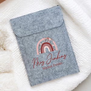 May include: Grey felt sticker folder with a rainbow and floral design. The text "Mrs. Jenkins Sticker Folder" is printed on the front.