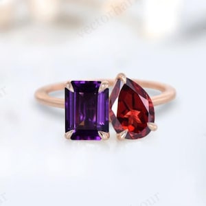 May include: A rose gold ring with two gemstones. The ring features a square emerald cut amethyst and a pear shaped garnet.